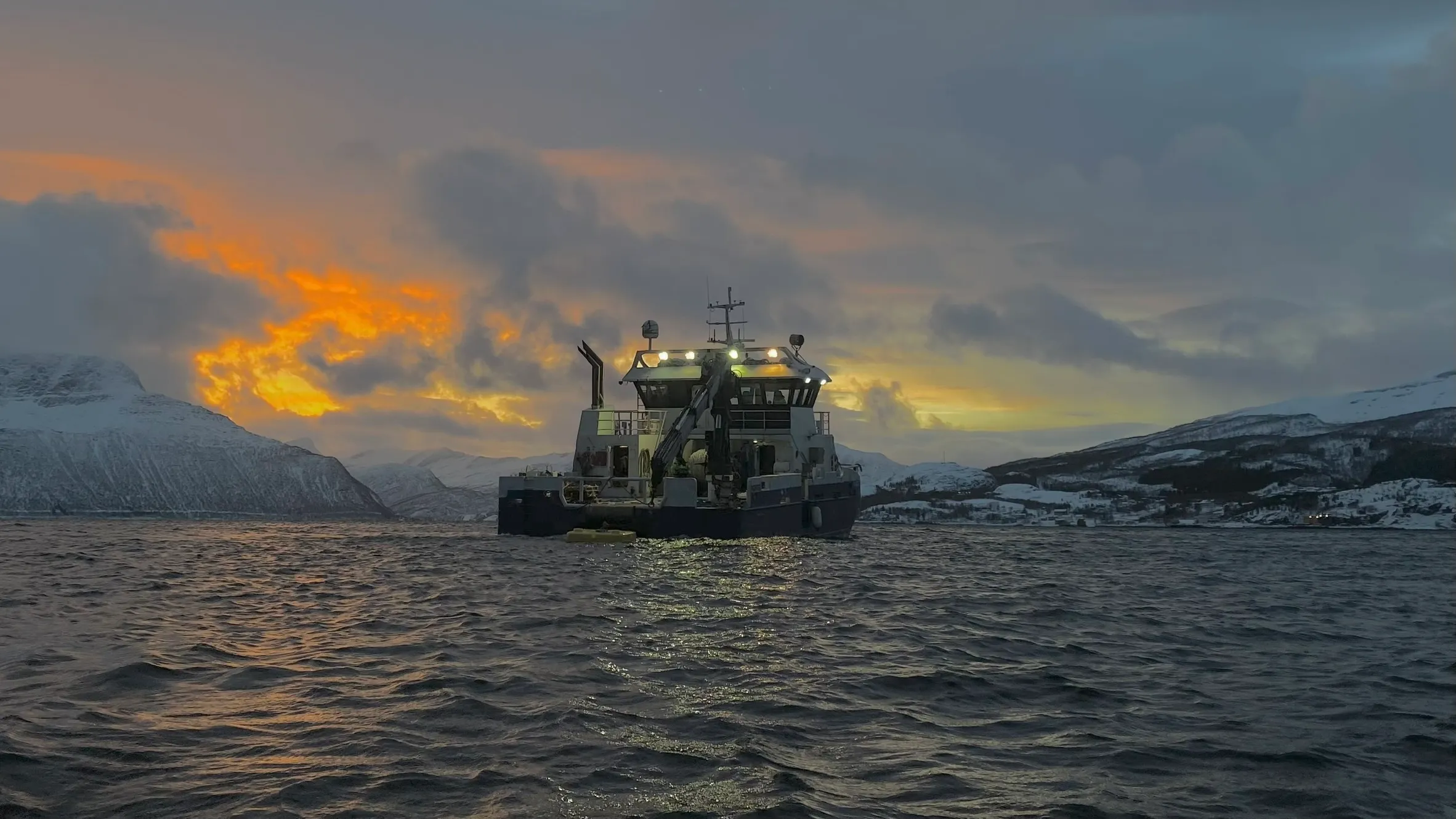 MS Akva Fighter servicebåt med snødekte fjell i bakgrunnen, Troms